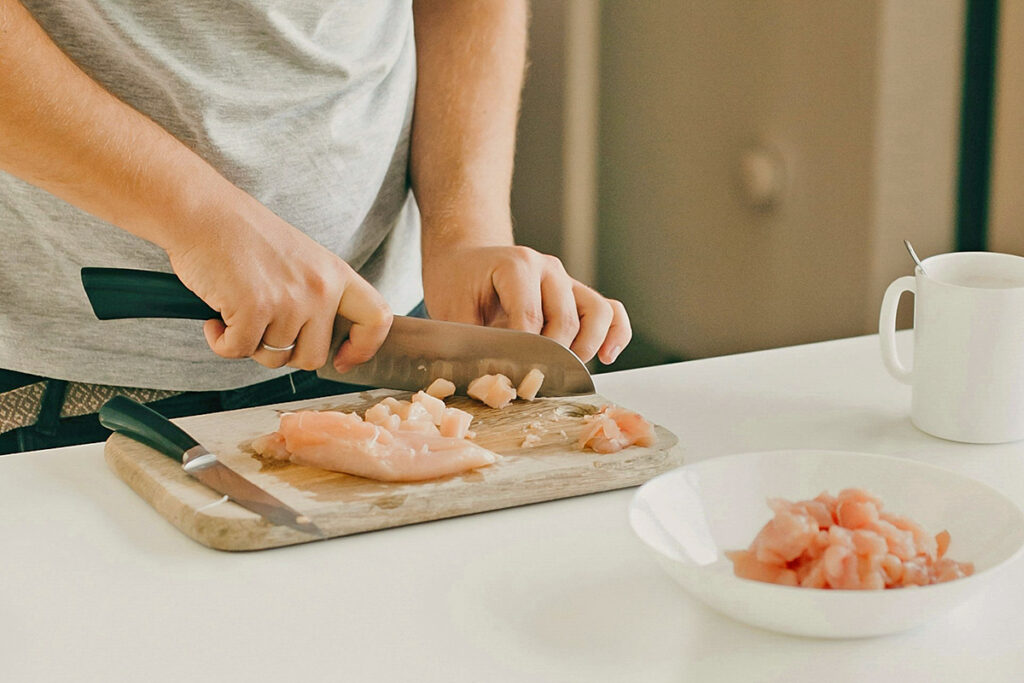 Cutting raw chicken on cutting board